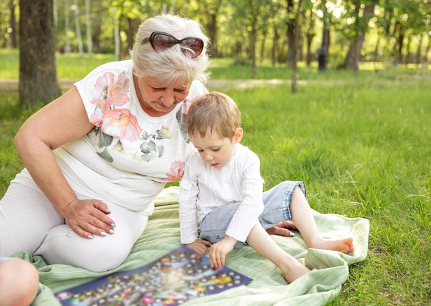 Glückliche Frau und Enkel, die Brettspiel zusammen im Park spielen