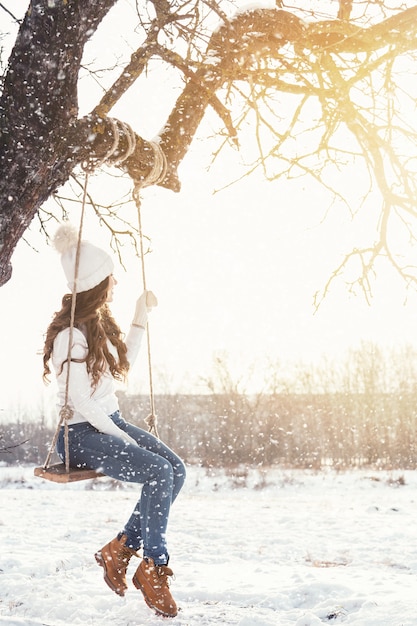 Glückliche Frau und Seil schwingen in Winterlandschaft