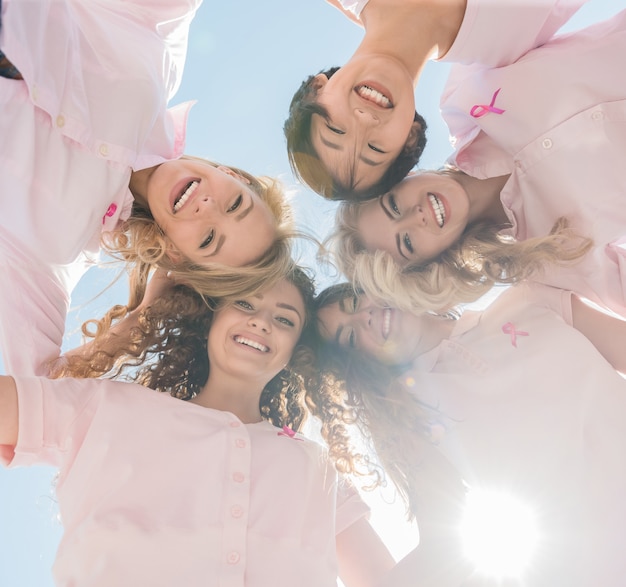 Glückliche Frauen im Kreis mit rosa Bändern.