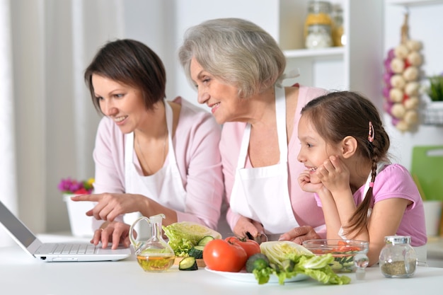 Glückliche Frauen mit dem kleinen Mädchen, das in der Küche kocht