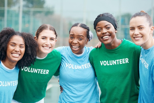 Glückliche Frauen porträtieren und Freiwillige im Sport, Fitness, Netball oder Outdoor-Übungen gemeinsam für die Gemeinschaft. Eine Gruppe sportlicher Spieler lächelt und umarmt sich in Teamsportmotivation oder ehrenamtlicher Arbeit auf dem Platz