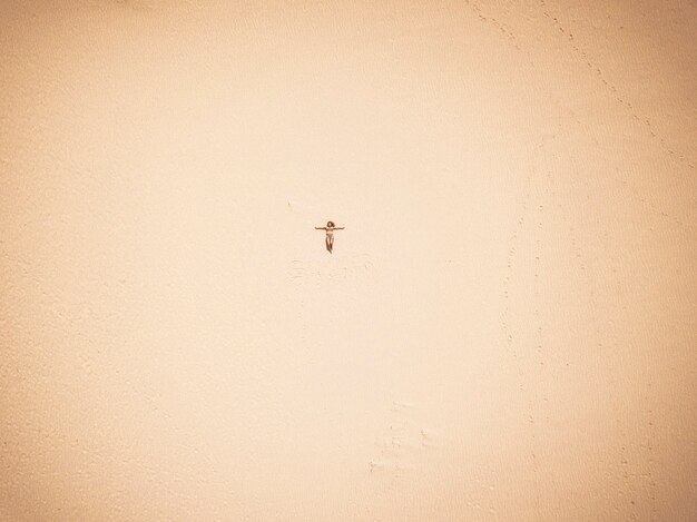 Glückliche freie kaukasierin legte sich am strand auf den sand und genoss die sommerferien - reise- und fernwehkonzept mit schönem mädchen aus vertikaler sicht - freizeitaktivitäten im freien