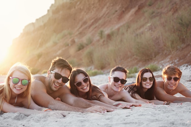 Glückliche Freunde, die auf Strandsand liegen