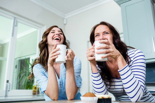 Glückliche Freunde, die bei Tisch Kaffeetassen halten