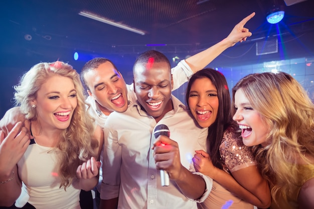 Glückliche Freunde, die beim Karaoke singen