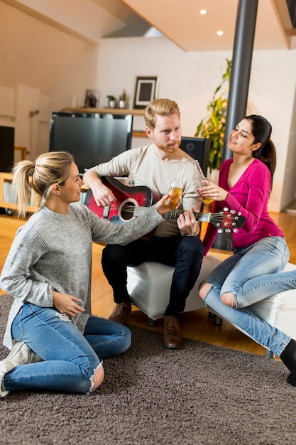 Glückliche Freunde, die Gitarre spielen und zu Hause Musik hören