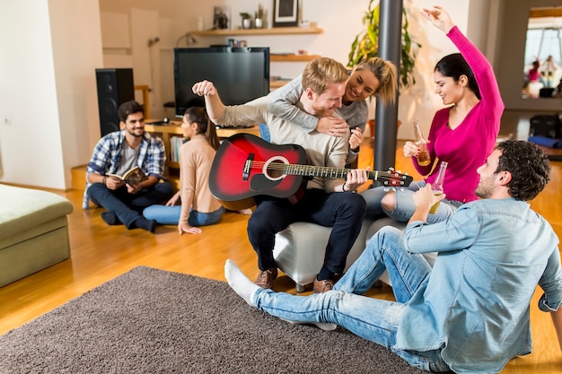 Glückliche Freunde, die Gitarre spielen und zu Hause Musik hören