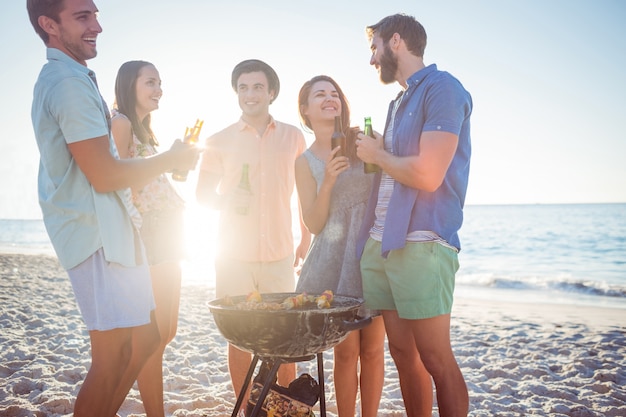 Glückliche Freunde, die Grill tun und Bier trinken