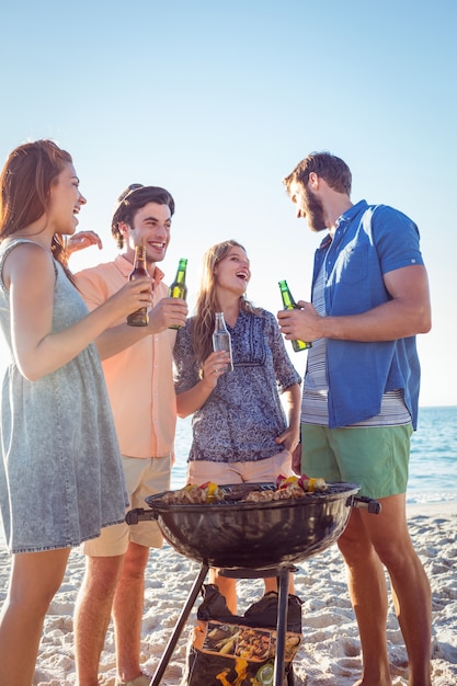 Glückliche Freunde, die Grill tun und Bier trinken