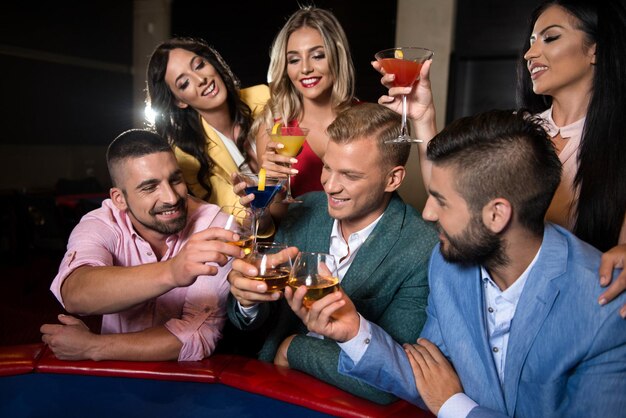 Glückliche Freunde, die im Casino spielen und Alkohol trinken