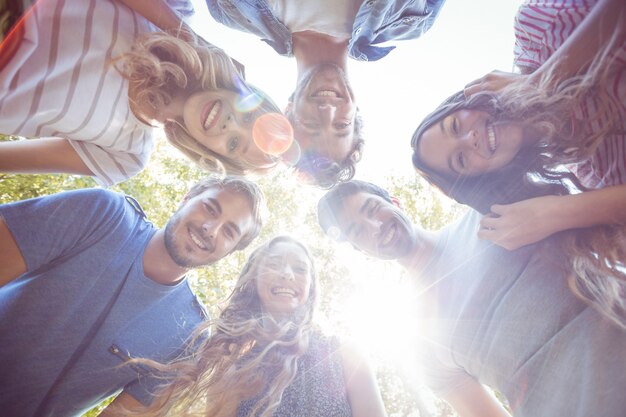 Glückliche Freunde, die im Kreis im Park kuscheln