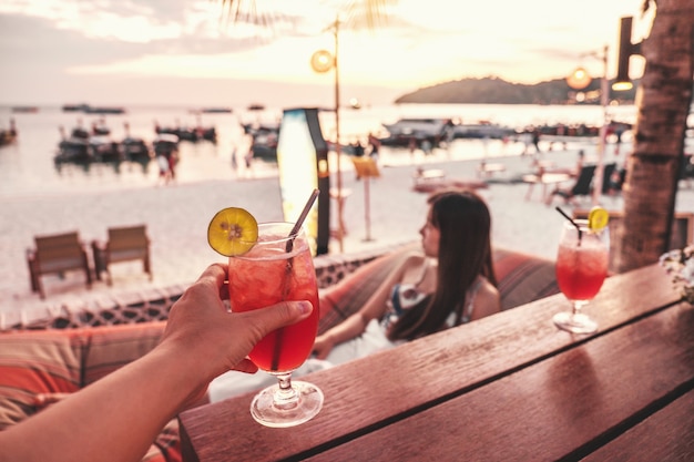 Glückliche Freunde, die mit tropischen Cocktails auf der Strandparty zujubeln