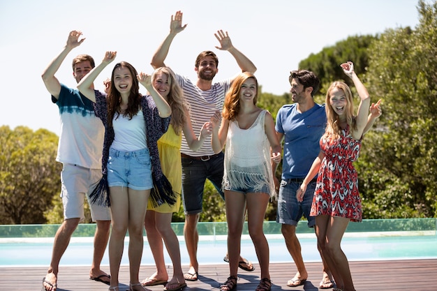 Glückliche Freunde, die nahe dem Swimmingpool tanzen