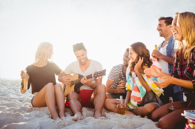 Glückliche Freunde, die Spaß beim Sitzen auf Sand haben