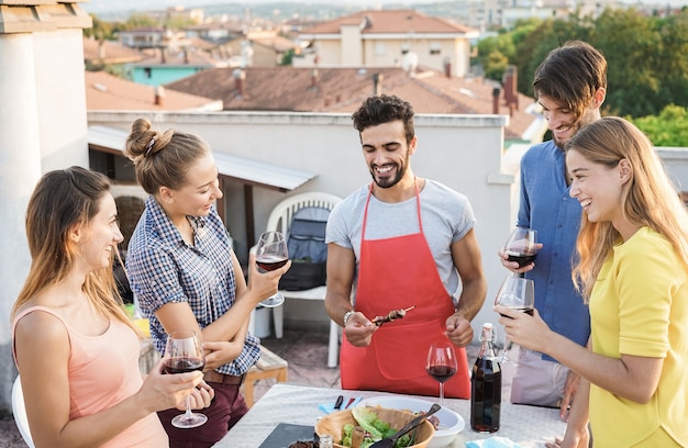 Glückliche Freunde, die zusammen Wein essen und trinken auf der Grillparty im Freien - Hauptfokus auf rechtem Mädchengesicht