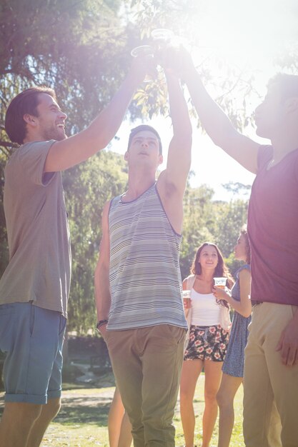 Glückliche Freunde im Park, der Biere isst