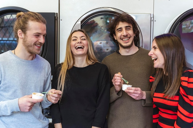 Foto glückliche freunde lachen, während sie gegen waschmaschinen stehen