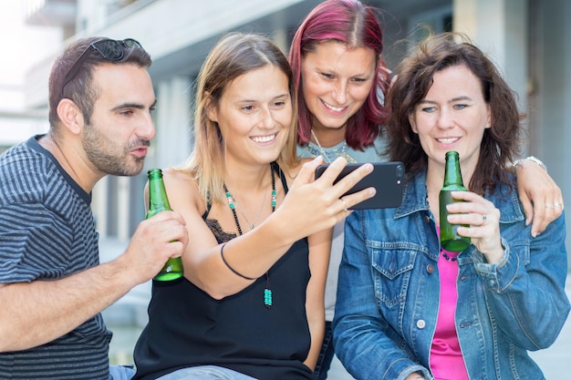 Foto glückliche freunde machen ein selfie, während sie in der stadt sitzen