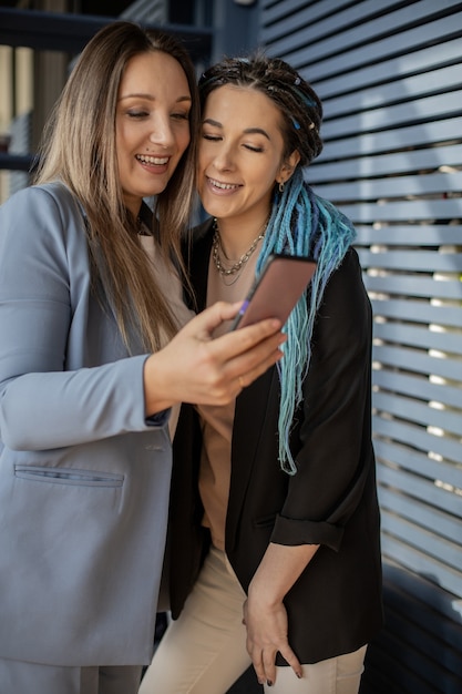 Glückliche Freundinnen, die zusammen Selfie-Fotografieren posieren, benutzen Smartphone und genießen Freundschaft