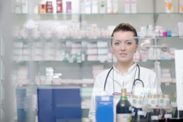 Glückliche fröhliche Apothekerin, Chemikerin, die in der Apotheke steht
