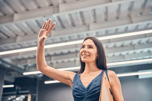 Glückliche fröhliche Geschäftsfrau Hand hoch, während sie Ordner mit Dokument hält