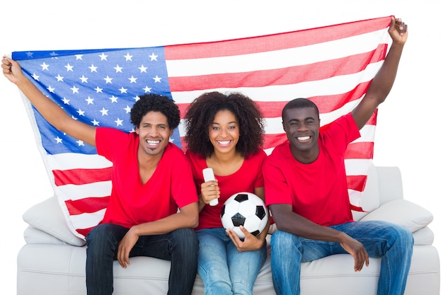 Glückliche Fußballfane im roten Sitzen auf Couch mit USA-Flagge