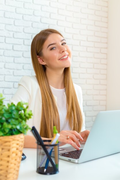 Glückliche Geschäftsfrau, die an dem Laptop im Büro arbeitet