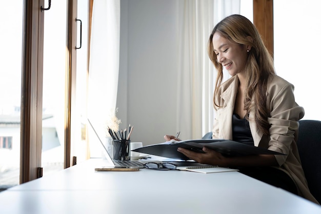 Glückliche Geschäftsfrau, die an ihrem Arbeitsplatz sitzt und mit einem Computer-Laptop arbeitet