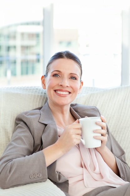 Glückliche Geschäftsfrau, die einen Tasse Kaffee trinkt