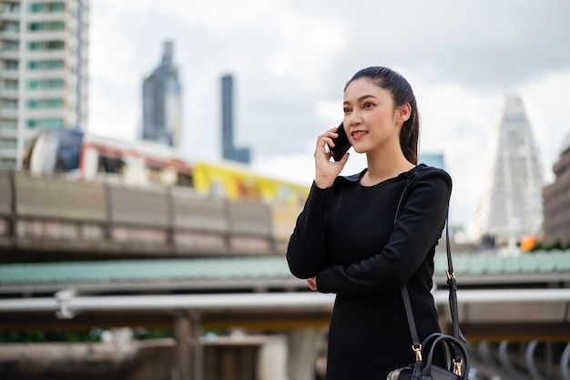 Glückliche Geschäftsfrau, die mit Handy in der Stadt spricht