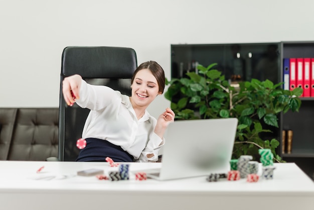 Glückliche Geschäftsfrau gewinnt im on-line-Kasino beim Spielen des Pokers im Büro am Arbeitsplatz