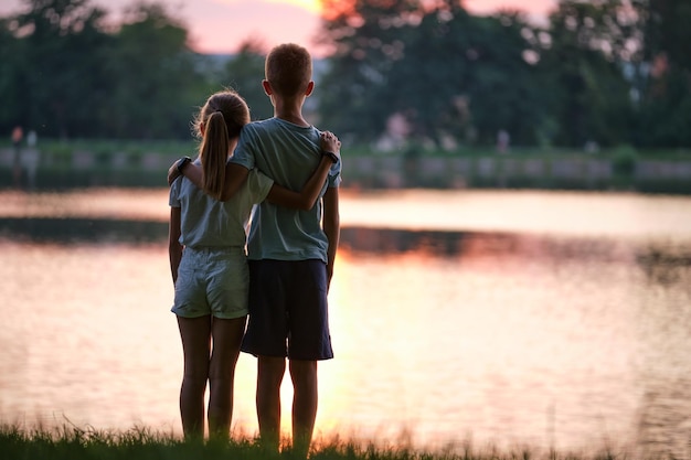 Glückliche Geschwister, die sich liebevoll im Sommerpark umarmen Junge Kinder, Bruder und Schwester, die sich im Freien umarmen Familienliebe und Beziehungskonzept