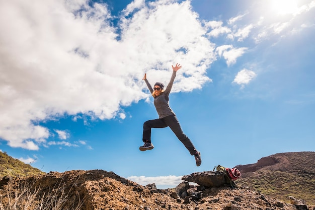 Glückliche gesunde Lebensstilfrau lächelt und springt in die Berge und hat Spaß bei der Trekking-Abenteueraktivität - Freiheit und Unabhängigkeit für Menschen im Naturpark im Freien