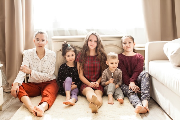 Glückliche große Familie von Brüdern und Schwestern, die auf dem Boden sitzen