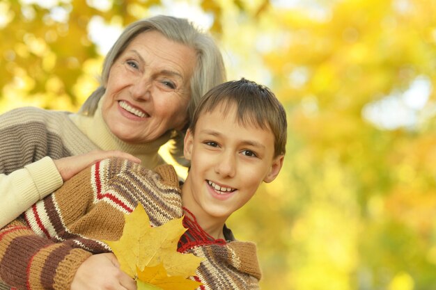 Glückliche Großmutter mit dem Jungen, der im Herbstpark ausruht