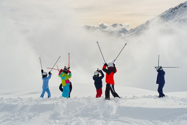 Glückliche Gruppe, die Ski auf dem Berg übt