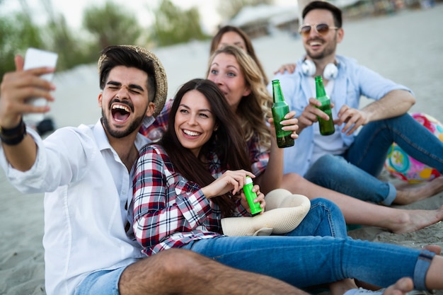 Glückliche Gruppe junger Leute, die im Sommer Spaß am Strand haben