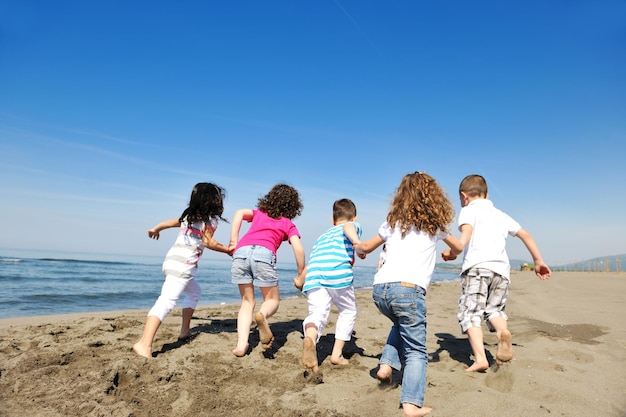 glückliche Gruppe junger Leute viel Spaß beim Laufen und Springen am schönen Sandstrand