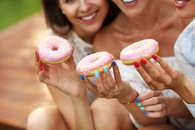 glückliche Gruppe von Freunden, die im Freien Donuts essen