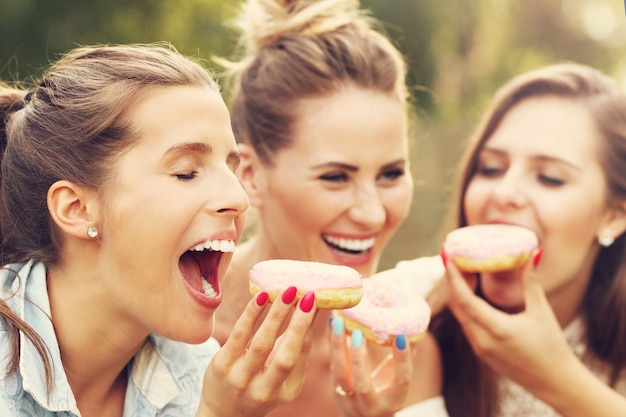 glückliche Gruppe von Freunden, die im Freien Donuts essen