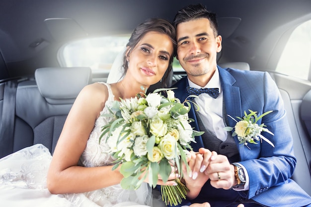 Glückliche, gutaussehende Jungvermählten sitzen zusammen in einem Auto, nachdem sie ihr Ja gesagt haben