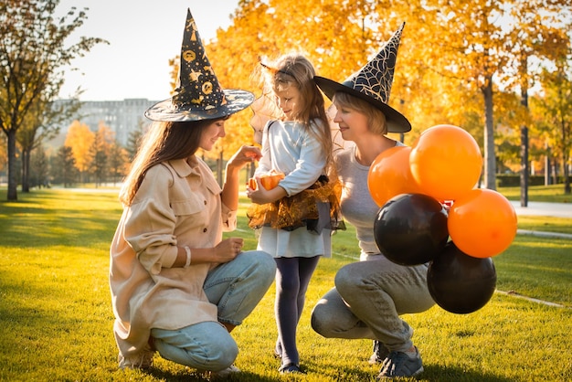 Glückliche halloween-mutter, großmutter und tochter haben spaß an den orangefarbenen kürbisballonen der feiertagsherbstparty