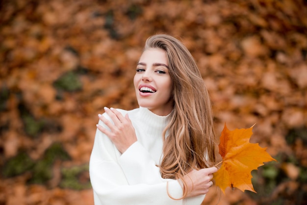 Glückliche Herbstfrau, die Spaß mit Blättern im Freien im Park hat