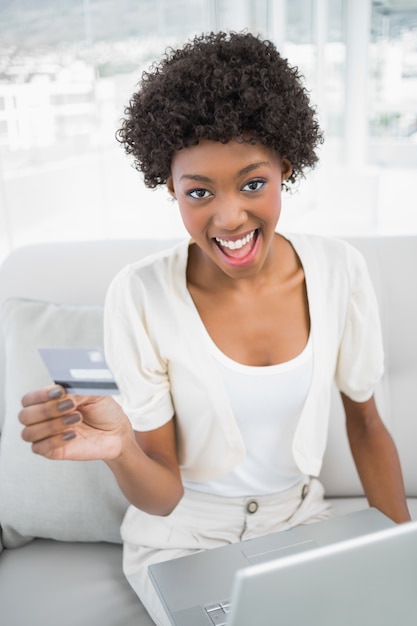 Glückliche herrliche Frau, die ihre Kreditkarte verwendet, um online zu kaufen