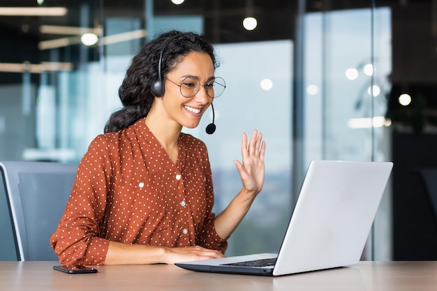 Glückliche hispanische Frau, die im Büro arbeitet, Geschäftsfrau mit Videoanruf-Headset, spricht und