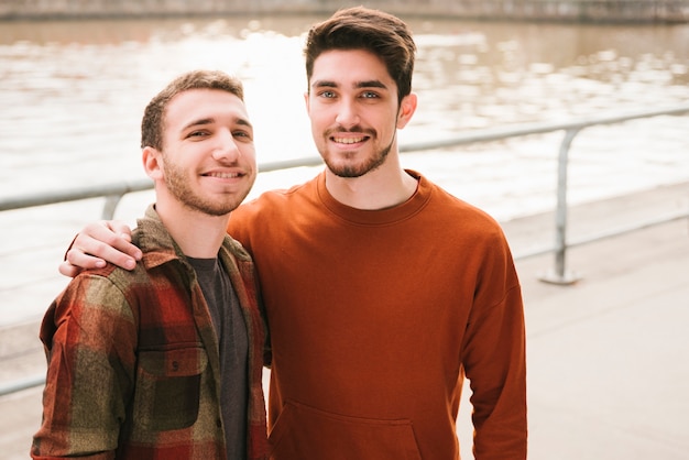 Foto glückliche homosexuelle paare, die auf flussdamm zusammensitzen