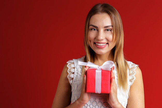 Glückliche hübsche junge Frau, die Geschenkbox hält