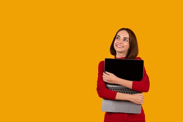 Glückliche hübsche junge Frau, die Laptop mit leerem Bildschirm umarmt