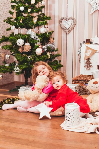 Glückliche hübsche Schwestern, die im weihnachtlich dekorierten Raum sitzen