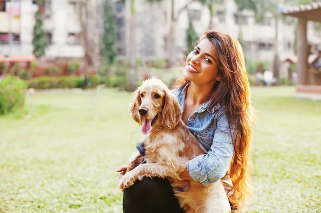 Glückliche indische Frau mit einem Hund in einem Park